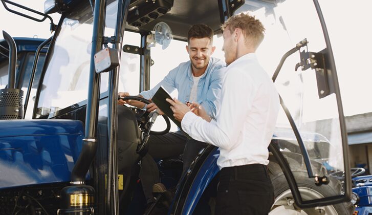 two men looking at heavy equipment one man is holding a tablet