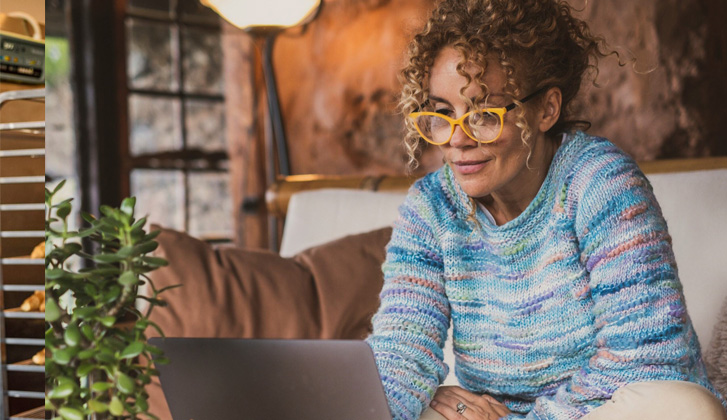 Lady sitting on a couch looking at her computer.