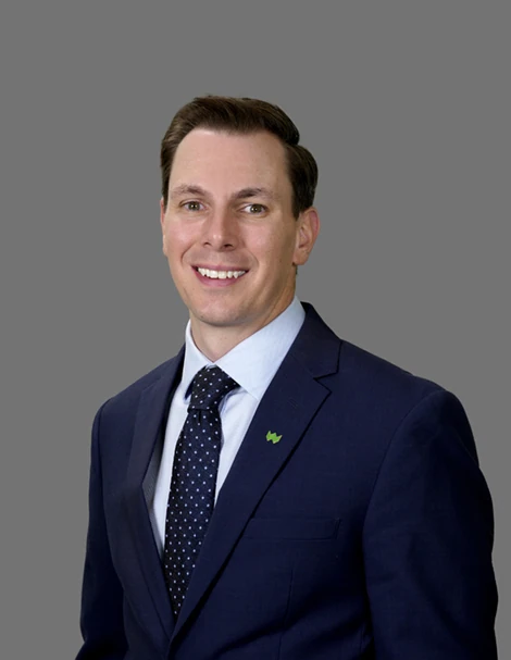 Professional headshot of Brent Moles in a blue suit, blue tie, and green wesbanco pin on the lapel, grey background