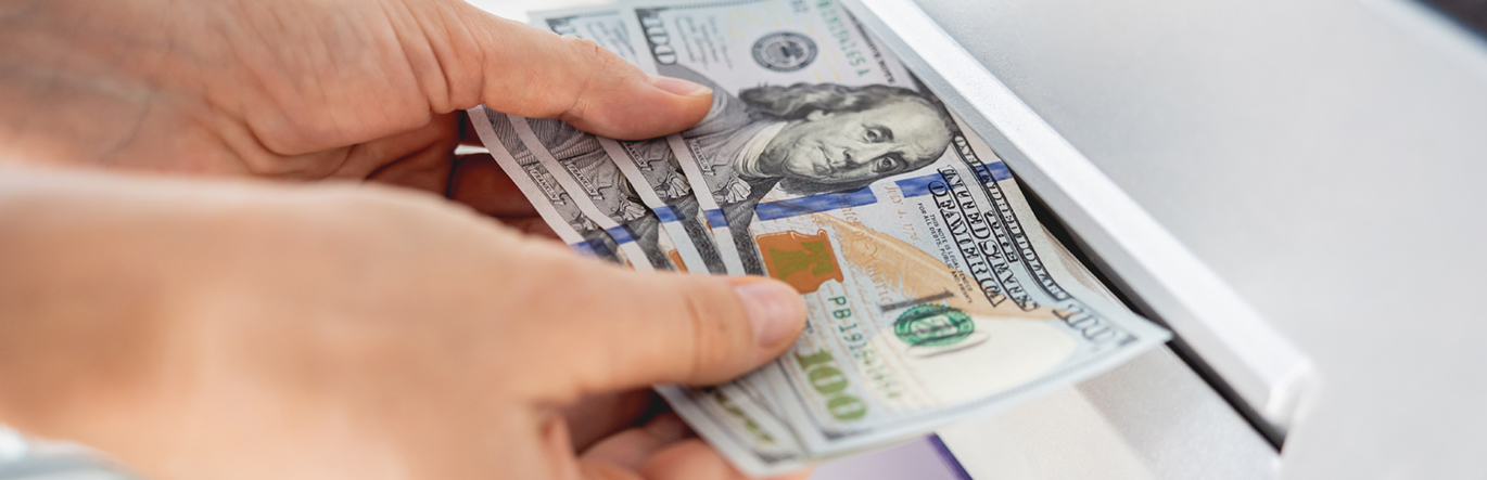 Young woman holding money in her hands after withdrawing the cash at the ATM.