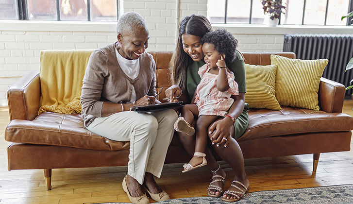 multigenerational family on couch looking at tablet together smiling