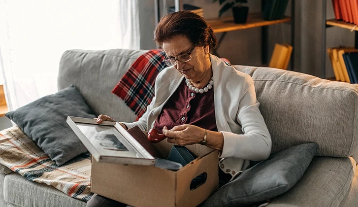 older woman reminiscing over a photograph and memory box